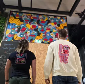L'artiste Razvan et Elodie Jouandet-Pujol, de dos, regardant une fresque murale à l'intérieur de la box Hornets Factory Mazamet.