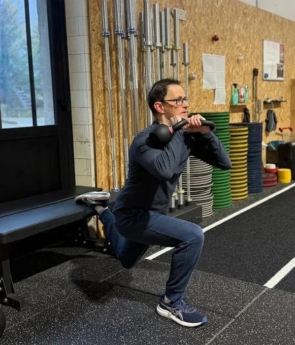 Geoffrey L., membre de Hornets Factory, en train de faire une Bulgarian split squat avec des haltères.